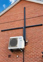 INABA DENKO SLIMDUCT SD-100 Black Decorative Trunking System Installed On Brick Facade For Air Conditioner Pipework